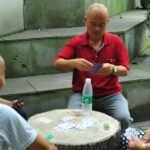 Grupo de idosos jogando cartas ao ar livre, sorrindo durante o jogo