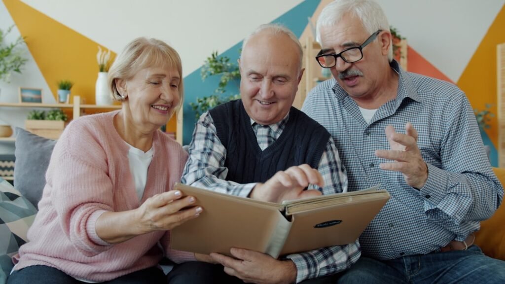 Idosos olhando álbum de fotografias antigas juntos, atividade de recordação usada na estimulação cognitiva para idosos com Alzheimer