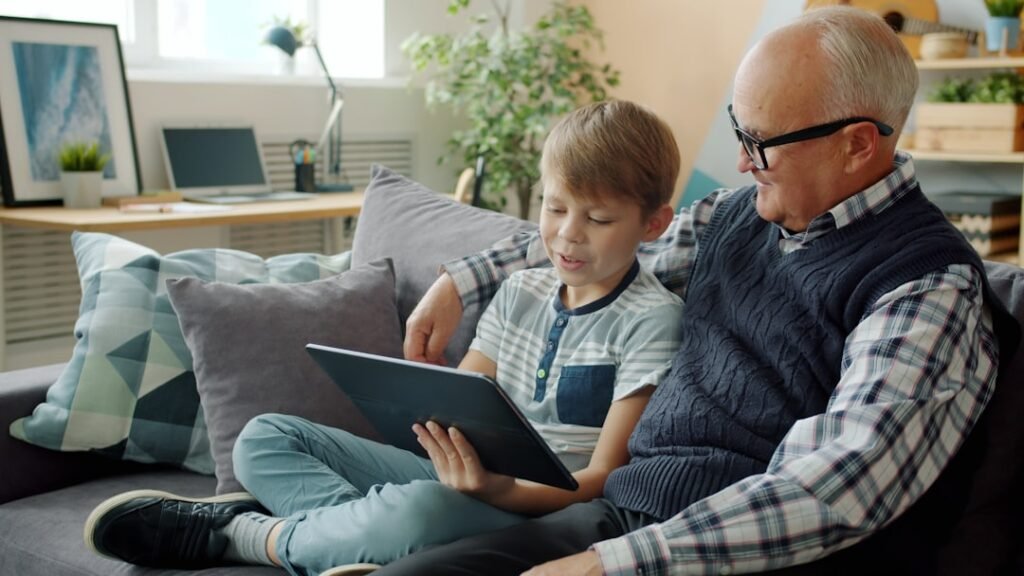Neto ensinando o avô a usar um tablet, exemplo de estimulação cognitiva para idosos através da tecnologia
