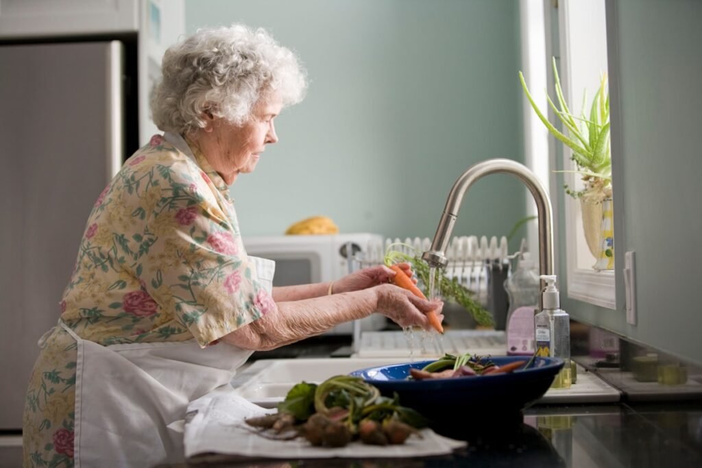 Senhora lavando legumes na pia como parte da rotina diária