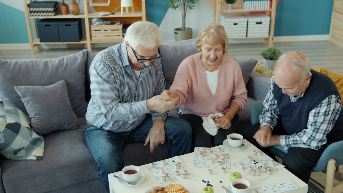 Jogos de memória para idosos: trio de idosos jogando bingo em sala de estar