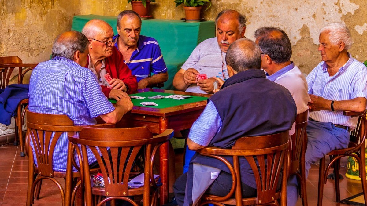 Jogos de memória para idosos: grupo de senhores jogando cartas ao ar livre