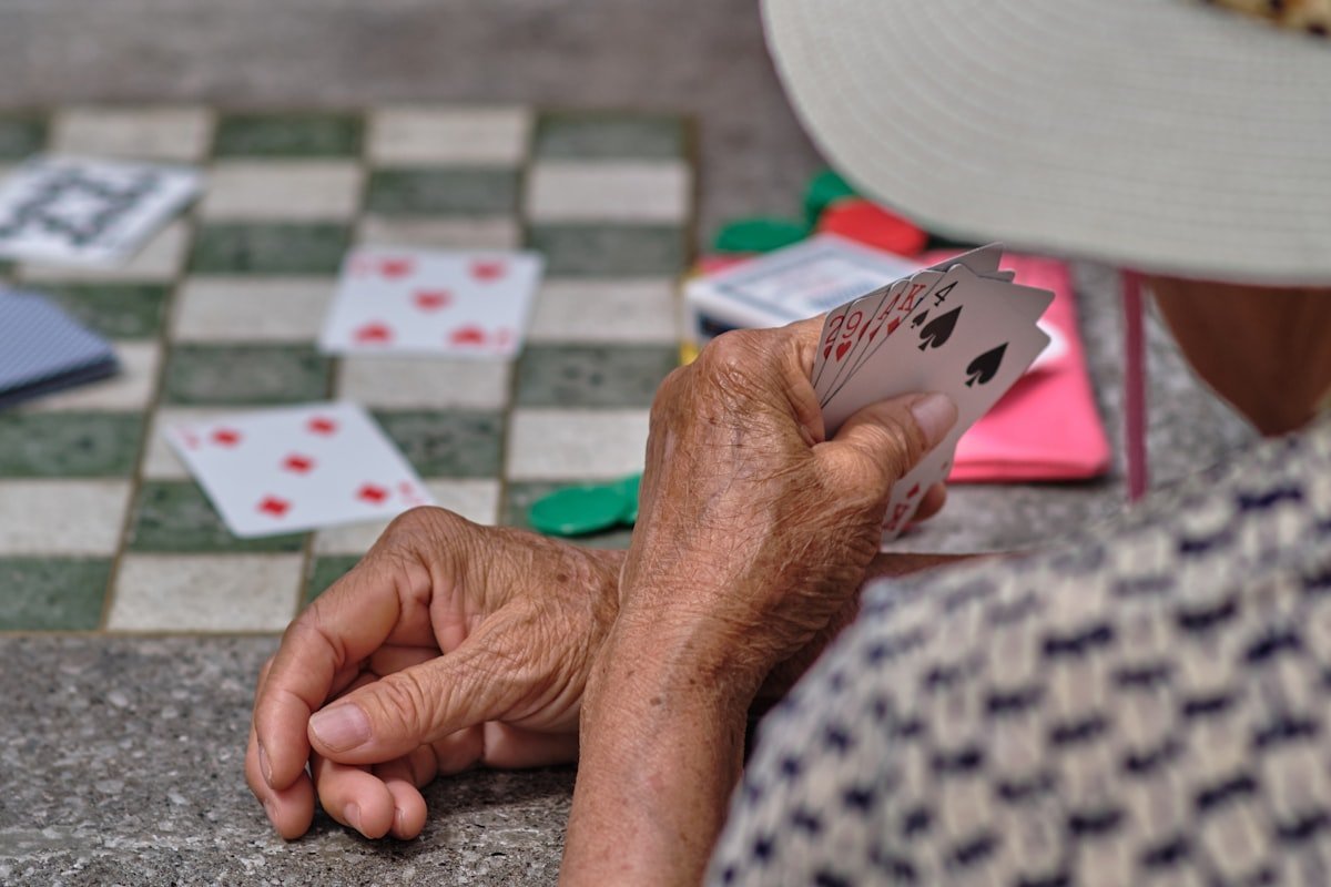 Jogos de memória para idosos: mãos de uma pessoa idosa segurando cartas de baralho
