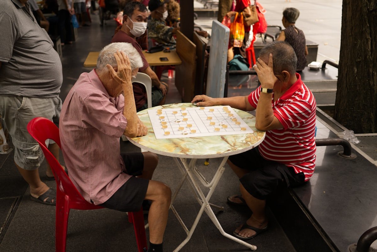 Jogos de memória para idosos: dois senhores concentrados jogando xadrez chinês