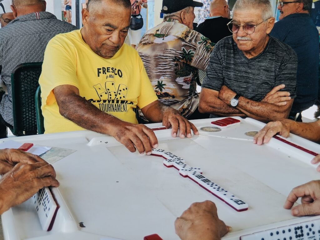 Idosos jogando dominó em mesa de torneio ao ar livre