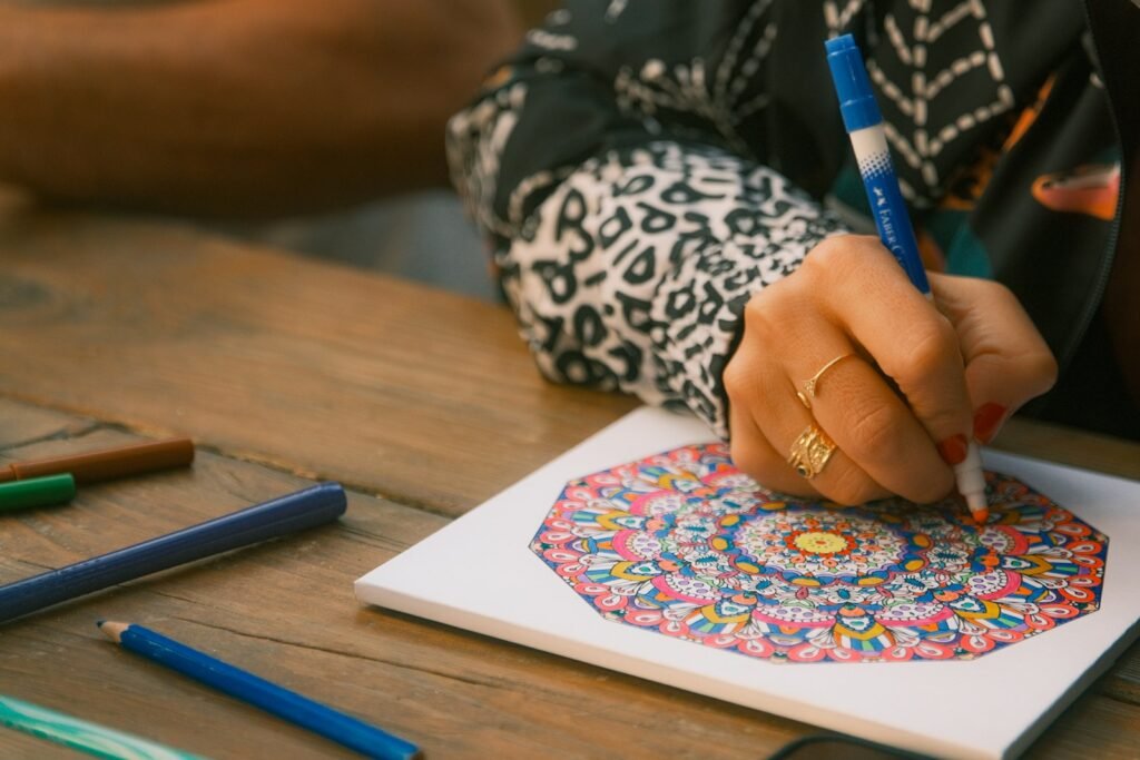 Pessoa colorindo mandala impressa com canetinha, atividade de coordenação motora indicada para nível leve