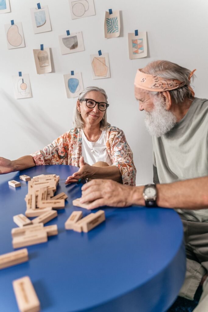 Casal de idosos jogando com peças de madeira sobre uma mesa azul