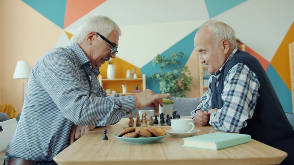 Dois idosos jogando xadrez com café e biscoitos sobre a mesa pela manhã