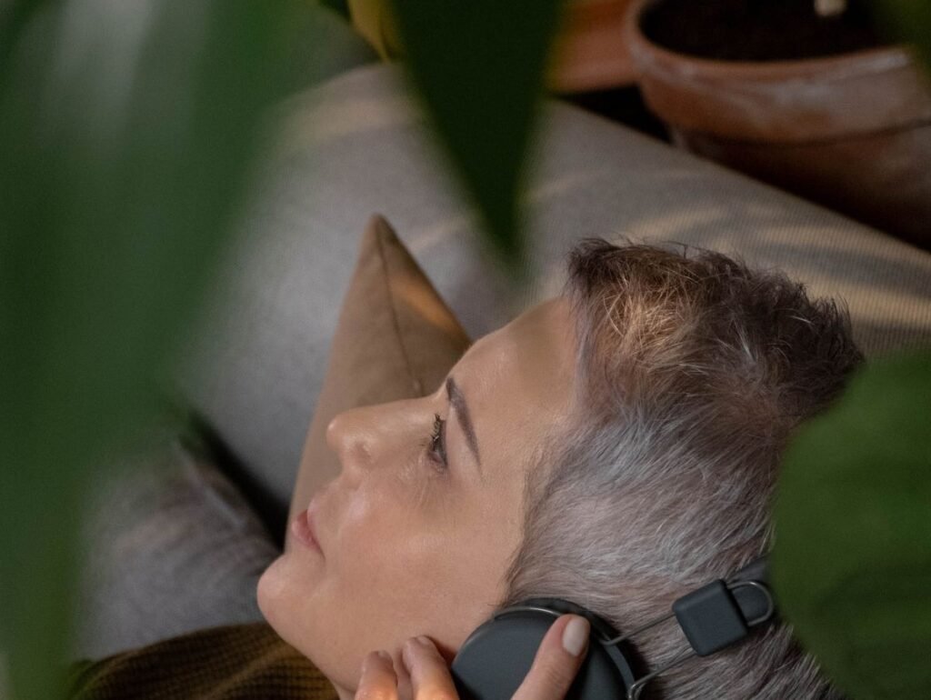 Mulher de cabelos grisalhos de olhos fechados ouvindo música em fones de ouvido